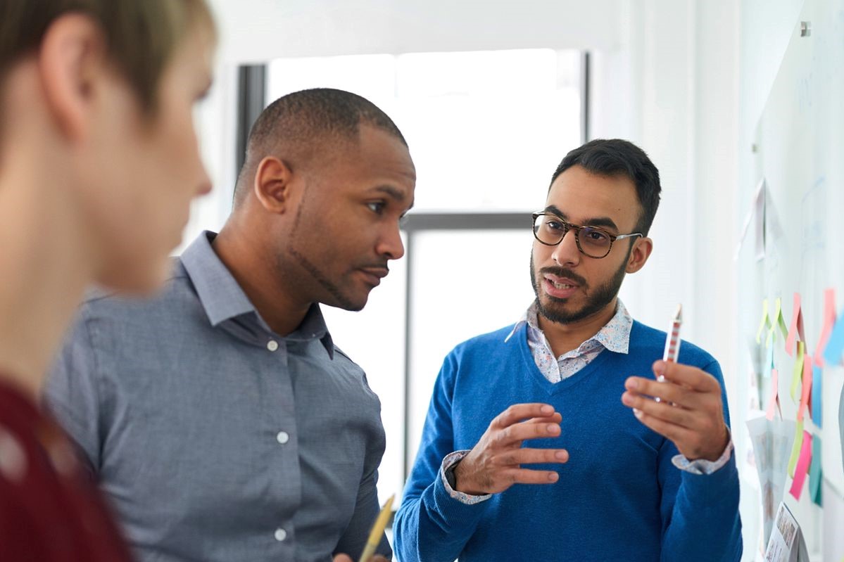 A team uses sticky notes and a whiteboard to brainstorm pricing strategies.